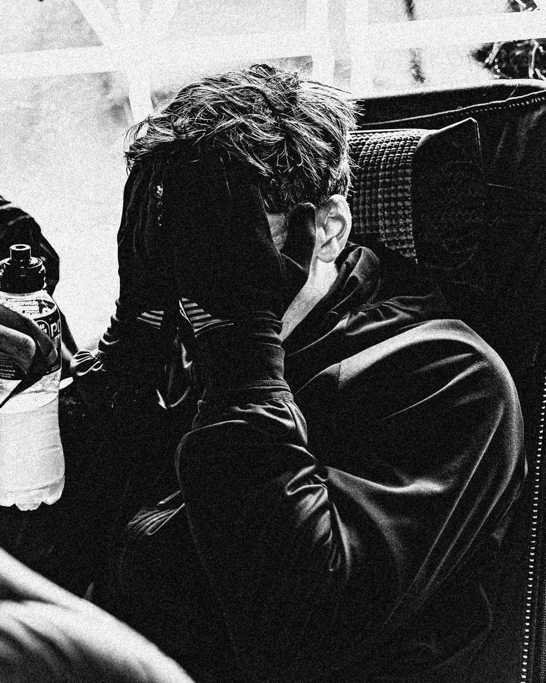 An exhausted Last Soul Ultra runner seated in camp with their face in their hands