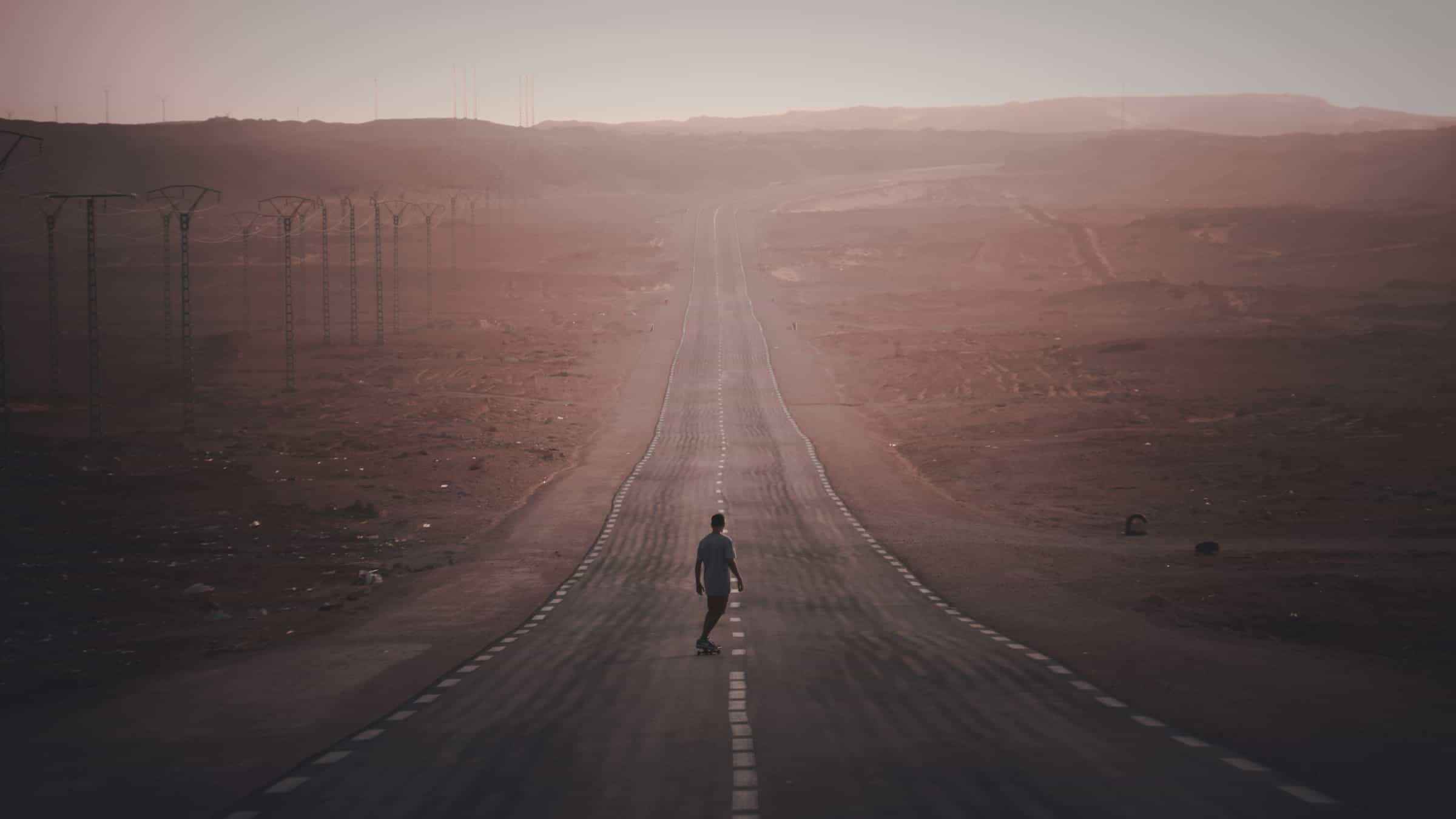 Lone runner on a long straight road through hazy desert